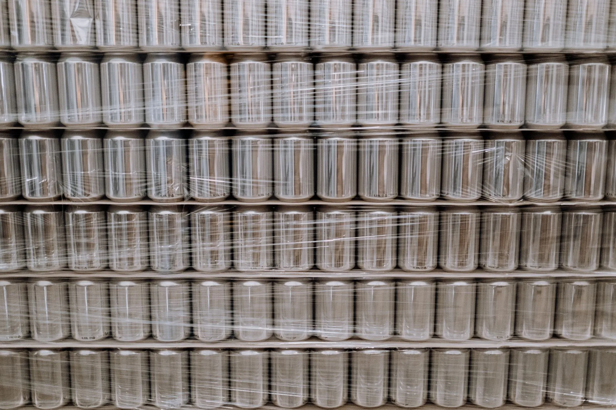 Palletised cans secured with multiple layers of transparent stretch film